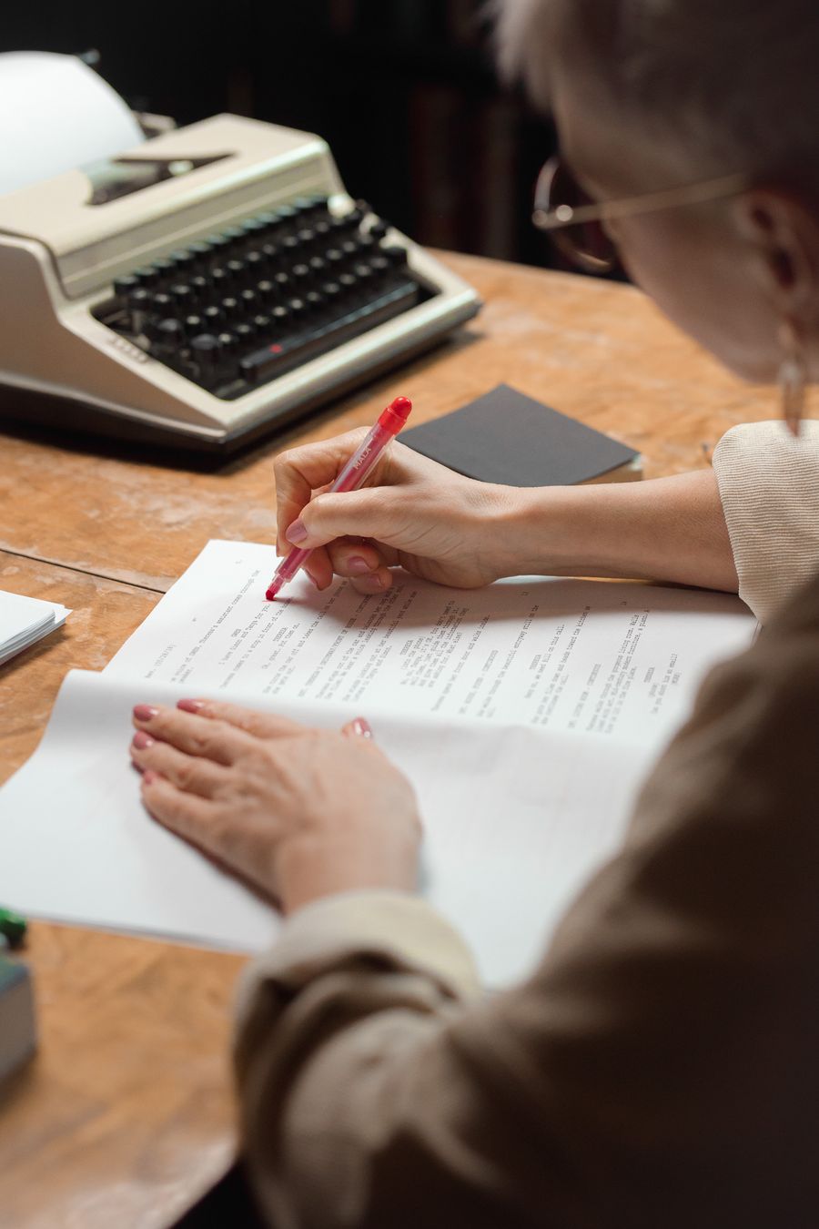 An author marking up a printed manuscript at a writing desk